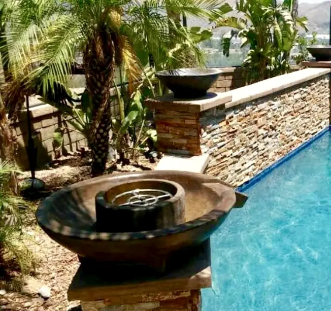 Fire-and-water bowls on stacked-stone pillars along the pool