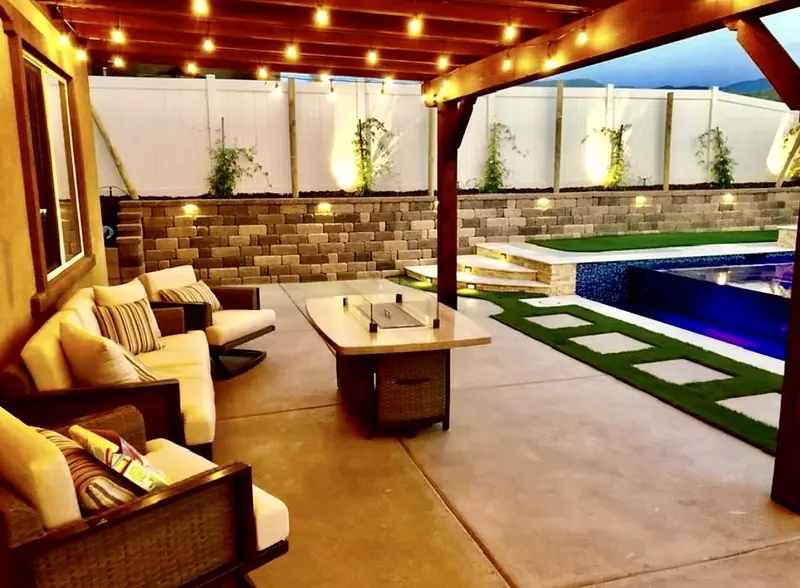 Covered lounge with a fire table and string lights, a few steps from the water