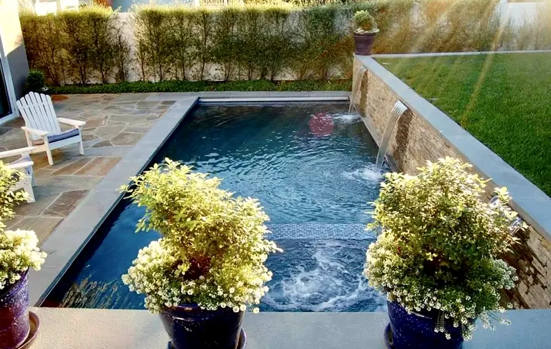 Lap pool lined with potted flowers and a stacked-stone wall