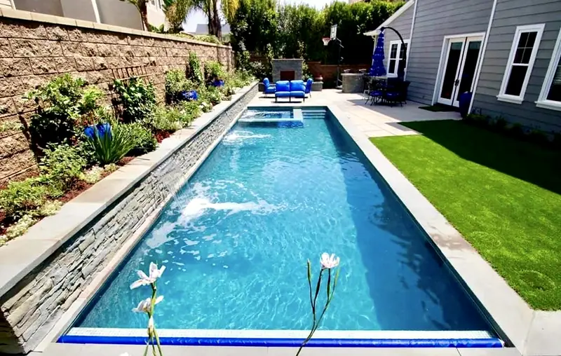 Long lap pool with a spillover spa and lawn edge