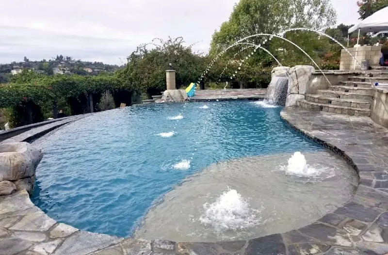 Finished remodel with deck jets arcing over a beach-entry shelf