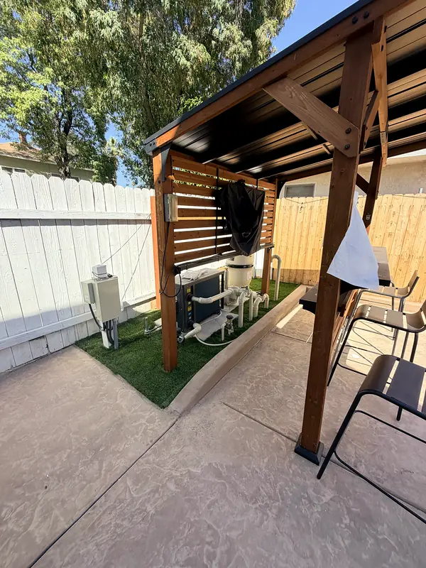 Wood pergola with privacy slats over a turf lounge area at the end of the pool