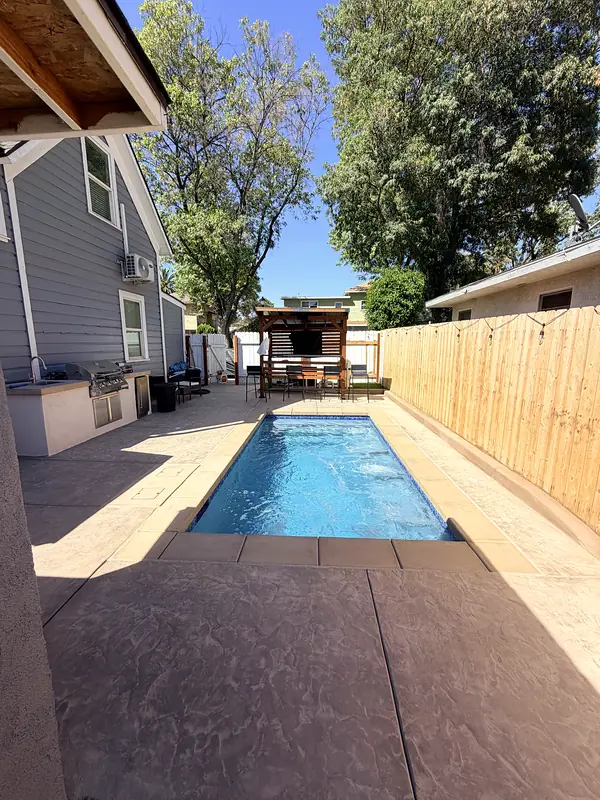 Looking down the side yard: kitchen, pool, and pergola lounge in one narrow space