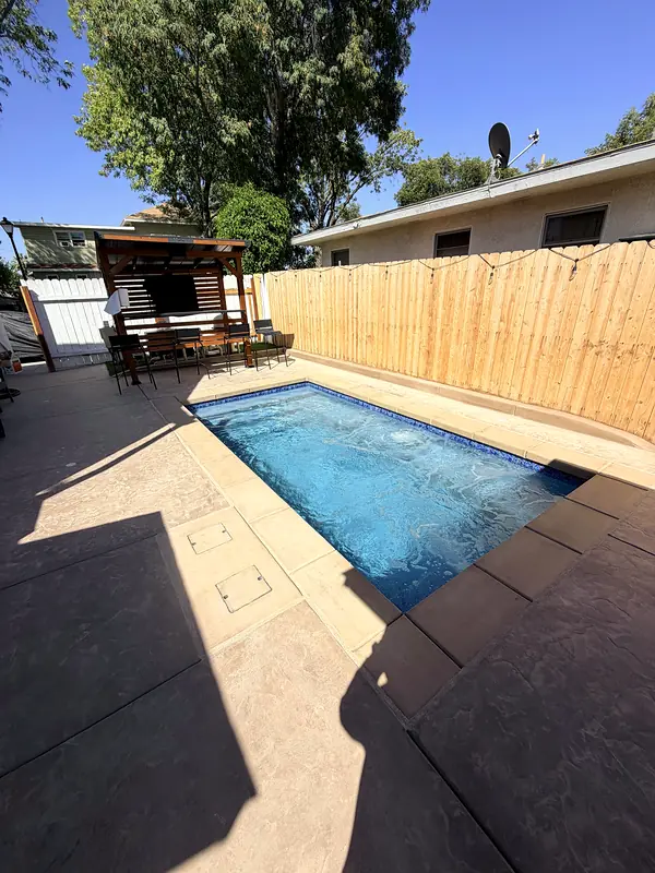 The side-yard pool from the house end, with the pergola and new fence behind it