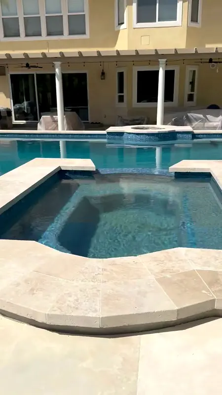 Finished remodel: raised spa with travertine coping beside the refilled pool