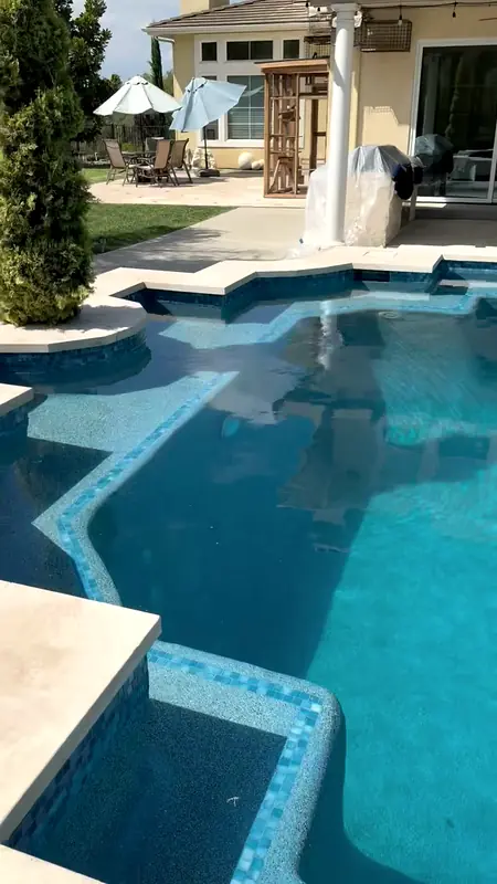 Glass-tile steps and travertine coping after the pool was filled