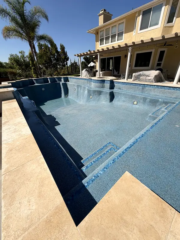 New blue interior with glass tile on the steps and a travertine deck, before the water went in